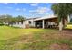 Exterior view of the white horse barn and stable with a lush green lawn at 13800 Ne Jacksonville Road, Citra, FL 32113