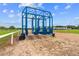 View of a blue metal horse racing starting gate on a dirt racetrack under a blue sky with fluffy white clouds at 13800 Ne Jacksonville Road, Citra, FL 32113