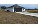 View of the side of a single story white house with a black garage door and exterior lighting at 17 Laurel Pass Ln, Ocala, FL 34480