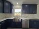 Bright kitchen boasts navy cabinets, stainless steel appliances, and farm sink under a window at 17 Laurel Pass Ln, Ocala, FL 34480