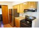 This is a kitchen with wood cabinets, stainless steel refrigerator and black cooktop at 1764 Se 169Th Avenue Rd, Silver Springs, FL 34488