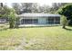 Backyard view of the screened-in pool area featuring a lush green yard and mature trees at 1764 Se 169Th Avenue Rd, Silver Springs, FL 34488