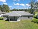 Exterior view of a home showcasing a spacious backyard, gray exterior and a well-manicured lawn under a blue sky at 211 Oak Lane Cir, Ocala, FL 34472