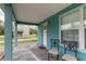 Covered front porch with seating and a white door on a charming light blue home at 307 Nw 10Th Ave, Ocala, FL 34475