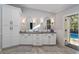 Elegant bathroom with double sinks, large mirrors, white cabinetry, and herringbone tile floors with access to the pool at 4245 Se 24Th Ter, Ocala, FL 34480
