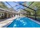 Large in-ground pool with screened enclosure, patio seating, and lush landscaping at 4245 Se 24Th Ter, Ocala, FL 34480