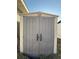 Utility shed featuring double doors, a peaked roof, and neutral color scheme in backyard at 43 Pine Radl, Ocala, FL 34472