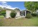 A backyard with a small patio, chairs, well maintained lawn, and a screened in porch at 6385 Sw 61St Ct, Ocala, FL 34474