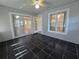 Enclosed sunroom patio with black tile flooring, ceiling fan, and sliding glass doors to the home at 6767 Sw 114Th Street Rd, Ocala, FL 34476