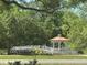 Scenic white gazebo with copper roof and bridge access, nestled in a lush green community landscape at 9380 Sw 84Th Ter # E, Ocala, FL 34481