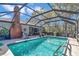 Sparkling screened pool with lounge chairs, a brick chimney and lush landscaping at 9844 Sw 198Th Cir, Dunnellon, FL 34432