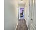 Hallway with wood floor leading to a Bedroom with a crib and purple accents at 1034 Se 65Th Cir, Ocala, FL 34472