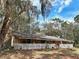 Ranch-style home featuring a charming white picket fence and a covered porch, shaded by mature trees and Spanish moss at 1370 Nw 120Th Ave, Ocala, FL 34482