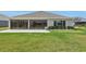 View of backyard with healthy grass, landscaping, and the home's screened in back patio at 5766 Henry Loop, The Villages, FL 32163