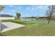 Backyard view with pond, healthy green grass, lush landscaping, and sunny skies at 5766 Henry Loop, The Villages, FL 32163