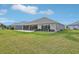 Backyard view with healthy green grass, landscaping, and the screened in patio at 5766 Henry Loop, The Villages, FL 32163