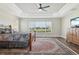 Elegant bedroom featuring tray ceilings, ceiling fan, and a large window overlooking the manicured lawn at 5766 Henry Loop, The Villages, FL 32163