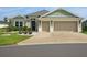 Charming home featuring a well-manicured lawn, detailed landscaping, and a spacious two-car garage with a custom driveway design at 5766 Henry Loop, The Villages, FL 32163