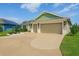 Charming home featuring a well-manicured lawn, detailed landscaping, and a spacious two-car garage with a custom driveway design at 5766 Henry Loop, The Villages, FL 32163