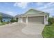 A spacious three-car garage with a decorative concrete driveway and lush landscaping at 5766 Henry Loop, The Villages, FL 32163