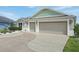 A spacious three-car garage with a decorative concrete driveway and lush landscaping at 5766 Henry Loop, The Villages, FL 32163