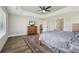 Spacious main bedroom features wood floors, a ceiling fan and ensuite bathroom with storage and an interior door at 5766 Henry Loop, The Villages, FL 32163