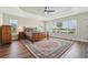 Large main bedroom features a tray ceiling, fan, wood floors and bright windows at 5766 Henry Loop, The Villages, FL 32163