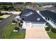 Aerial view of a light blue house with a three car garage, pergola, and well-manicured lawn at 7014 Elaine Ct, The Villages, FL 34762