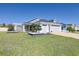 View of front lawn with a light blue house, pergola, and well-manicured landscaping at 7014 Elaine Ct, The Villages, FL 34762