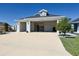 Three-car garage with open doors revealing a spacious interior, and decorative landscaping at 7014 Elaine Ct, The Villages, FL 34762