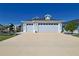 Three car garage with modern doors and concrete driveway, and decorative landscaping at 7014 Elaine Ct, The Villages, FL 34762