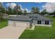 New home featuring a large driveway, 3 car garage, a blue exterior, and a well-manicured lawn at 9975 Sw 39Th Ter, Ocala, FL 34476
