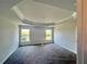 Carpeted bedroom featuring a tray ceiling and natural light from the windows at 4365 Sw 90Th Pl, Ocala, FL 34476