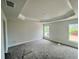 Light-filled bedroom with plush carpeting, tray ceiling, and a view of the serene neighborhood at 4365 Sw 90Th Pl, Ocala, FL 34476