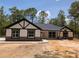 Charming single-story home featuring black trim, stone accents, and a well-maintained lawn surrounded by mature trees at 6150 Sw 123 Ave Rd, Dunnellon, FL 34432