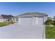 Two-car garage home featuring a concrete driveway and lush green lawn at 6877 Minchew Cir, The Villages, FL 34762