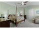 Spacious main bedroom with a four-poster bed, ceiling fan and adjoining bathroom at 6877 Minchew Cir, The Villages, FL 34762