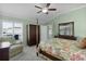 Comfortable main bedroom featuring a four-poster bed, ceiling fan, and plenty of natural light at 6877 Minchew Cir, The Villages, FL 34762