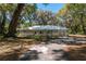 Charming single-story home with mature trees, a long driveway, attached garage, and light gray paint color at 14100 Ne 40Th Ct, Anthony, FL 32617