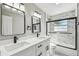 Modern bathroom features a double sink vanity with white marble countertop and a glass-enclosed tub with tiled walls at 2607 Verde Ln, Winter Park, FL 32792