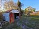 Rusty metal storage shed in backyard with adjacent swing set and mature landscaping at 911 Oak Dr, Leesburg, FL 34748