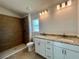 Bathroom featuring double vanity, granite counters, and a wood-look tile shower at 4498 Sw 90Th Lane Rd, Ocala, FL 34476