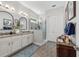 Bathroom with double sink vanity, frameless shower, modern lighting, and gray wood look tile flooring at 9307 San Jose Blvd, Howey In The Hills, FL 34737