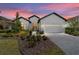 Stunning single-story home featuring manicured landscaping, a paver driveway, and a two-car garage at sunset at 9307 San Jose Blvd, Howey In The Hills, FL 34737