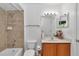 Neutral bathroom featuring a tub, tiled wall, light wood cabinet, and modern vanity at 1201 Creekview Ct, St Cloud, FL 34772