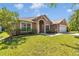 An exterior view of a tan home featuring a well-maintained lawn and manicured landscaping at 1201 Creekview Ct, St Cloud, FL 34772