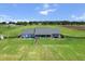 View of a sprawling single-story home with a covered back patio, surrounded by fenced pastures and greenery at 23376 Nw 27Th St, Morriston, FL 32668