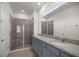 Bathroom showcasing double sinks with granite counters, grey cabinets and glass enclosed shower at 5530 Nw 40Th Loop, Ocala, FL 34482
