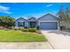 Beautiful blue single-story home with a well-kept lawn, landscaped garden beds, and an attached garage at 9230 Sw 66Th Loop, Ocala, FL 34481