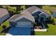 Aerial view of a well-maintained property featuring lush lawn, mature trees, and a beautifully patterned driveway at 13968 Se 96Th Cir, Summerfield, FL 34491